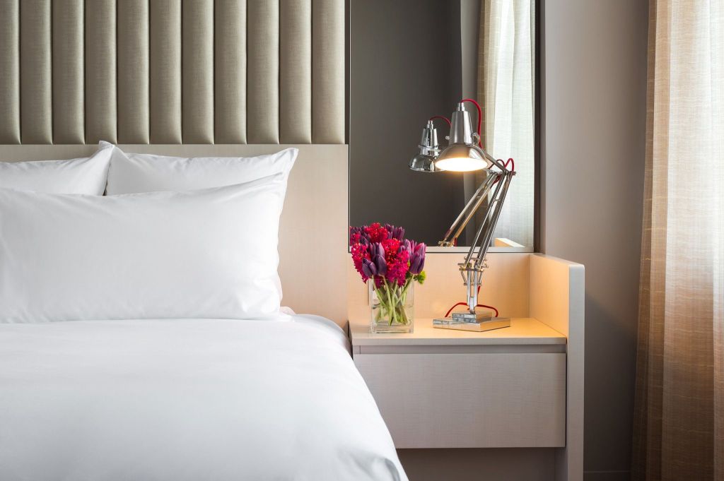 Hotel bed with white bedding and a nightstand with a lamp