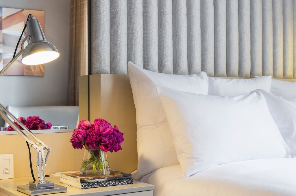 White pillows on a hotel bed and a nightstand with a lamp