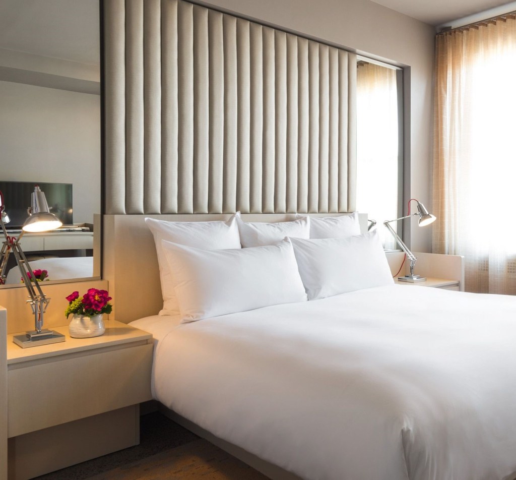 A king hotel bed with white bedding and a nightstand