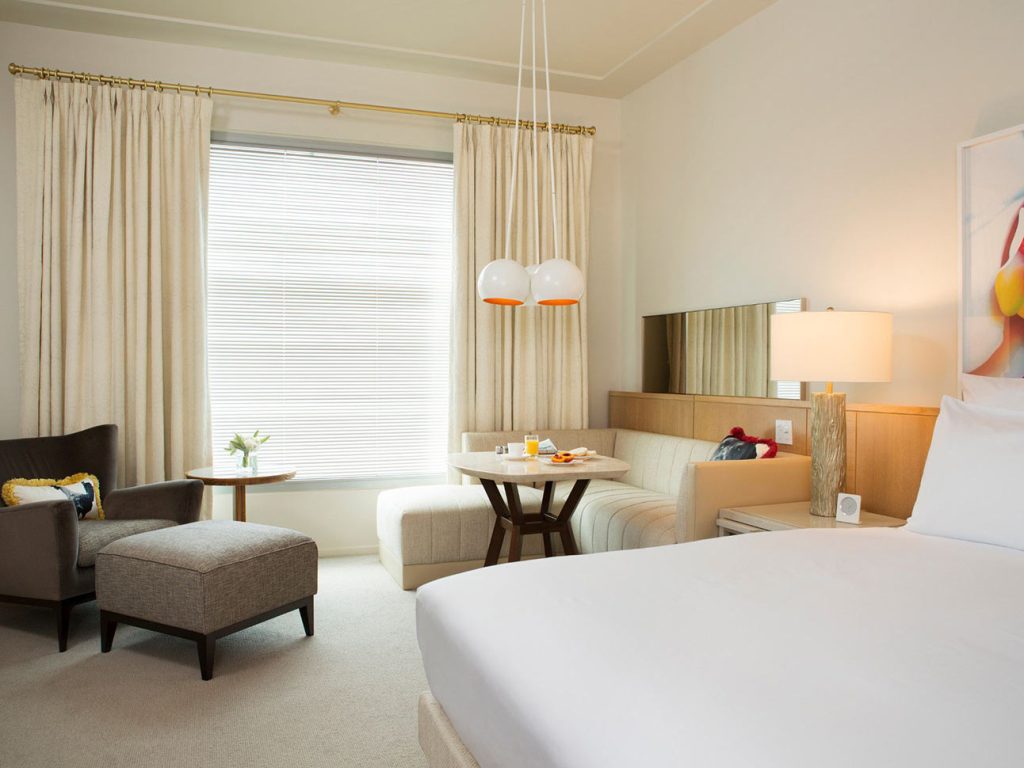 Chair with footstool, couch, table and bed in a Luxury King room at 21c Bentonville