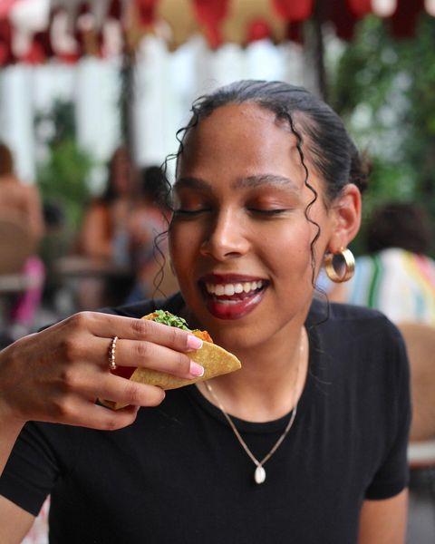 An attractive woman bites into a taco
